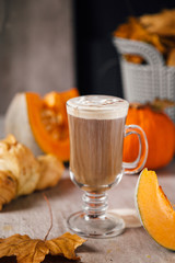 Pumpkin latte and croissant on the table with pumpkin slices