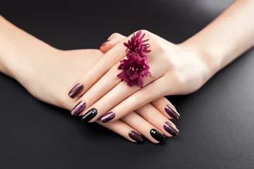 Fototapeten Black and burgundy manicure with flowers on black background. Gel nail polish with mirror powder pigment © maryviolet