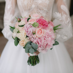 Bride in beautiful dress holds a wedding bouquet.