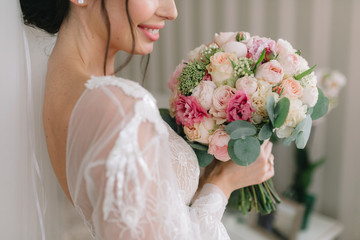 Bride in beautiful dress is a smiling and holds a wedding bouquet.