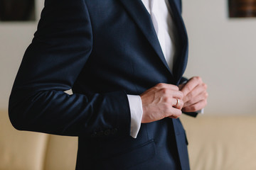 Groom wedding morning preparation. Young and handsome groom getting dressed in a wedding shirt.