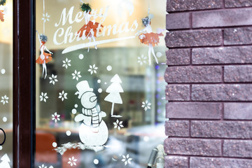 Shop-window decorated with temporary drawing of snowman and christmas tree made of artificial snow. New year and xmas holidays city decor