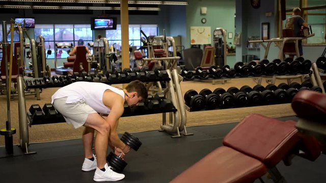 Young bodybuilder using a heavy dumbbell doing goblet squats.