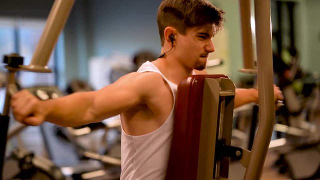 Front side closeup of handsome teen bodybuilder doing rear delt flys.