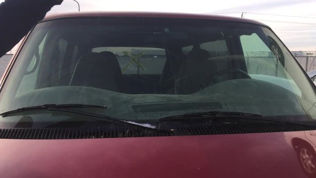 Angry man vandalizes windshield with metal bar with glass chars exploding into air from repeated strikes. 