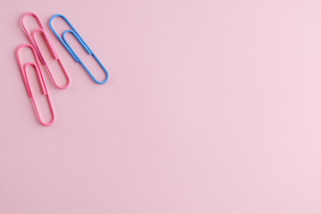 Colored paper clips on a pink background.