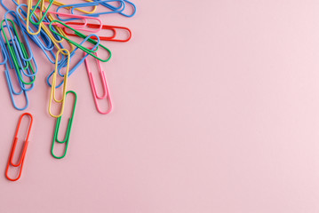 Colored paper clips on a pink background.