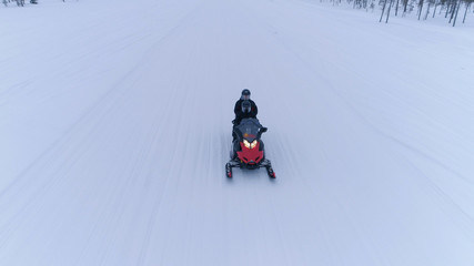 Fototapeta na wymiar CLOSE UP: Couple driving snowmobile through snowy wintry landscape in Finland