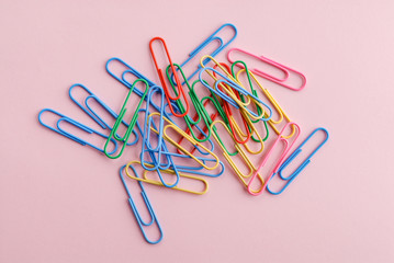 Colored paper clips on a pink background.