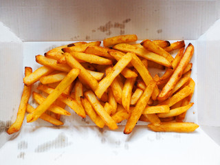 French fries box, fried potatoes french fries in unwrapped brown paper box soiled with oil, top view