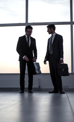 two businessmen talking standing in the office hall