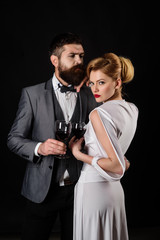 Handsome man with glass of wine hugs beautiful woman. Elegant couple with red wine. Romantic couple spending time together. Happy couple drinking glass of wine. Girl flirting with man with glass wine.