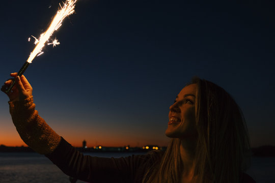 Happpy woman holding roman candle in hand