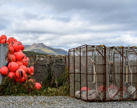 Crab Traps and Buoys Stacked on a Dock in Dutch Harbor Unalaska with Mountains in the Background