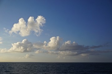 Fototapeta premium Thick white clouds over the horizon in a deep blue sky somewhere in the North Pacific Ocean between Sitka, Alaska, and Victoria, British Columbia, Canada.