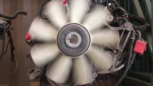 Car engine fan blades spin by hand close up in mechanical shop.