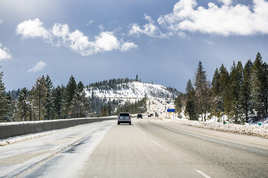 Cars Driving On I80 Interstate Through The Sierra Mountains Close To Lake Tahoe On A Sunny Winter Day; The Road Has Been Cleared On Snow, California