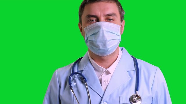 Young doctor stand and looking into camera on green chroma key background