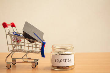 Graduation hat on cart or trolley with glass jar saving money scholarship for education in future on wood table,vintage,minimal.