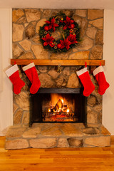 Fireplace designed for Christmas with four red stockings, a bell and beautiful wreath.