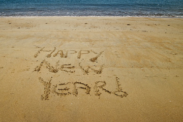 Happy New Year written in the golden sand of Little Kaiteriteri beach