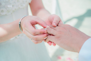 Marriage hands with rings. bride wears the ring on the finger of the groom in beach Phuket, Thailand.
