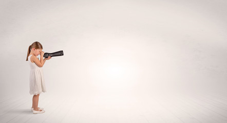 Cute little girl looking through spyglass to an empty space
