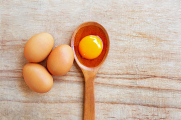 Egg yolk on wooden spoon, Wooden background.