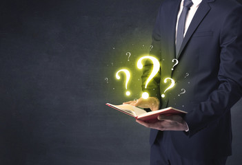 Businessman holding a book with question mark symbol.