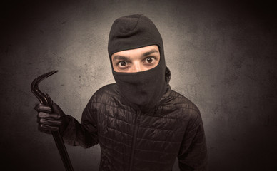 Burglar standing in black clothes and balaclava on his head.