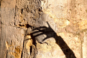 Strange shadow of one hand on an old stone wall. Black shadow, female hand. Background, texture,...