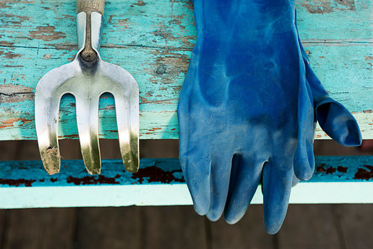 Hoe And Rubber Glove On A Wooden Table