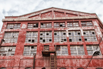 Facade of the old production building with potreskanny paint against the background of the blue sky with clouds.