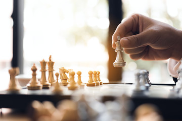 Close up businessman hand moving the king in a chess game for win.