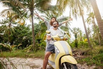 Happy multinational couple traveling on a motorbike in the jungle, honeymoon, vacation, travel...