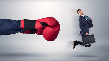 Giant hand gives a kick to a small employee businessman