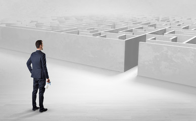 Businessman getting ready to enter the labyrinth with objects in his hand concept

