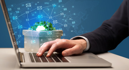 Businessman hand sending a bunch of messages on laptop with cloud computing concept
