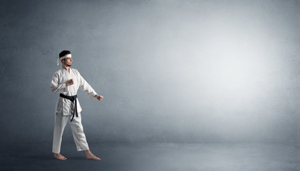 Small karate man fighting in an empty grey copy space