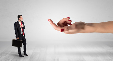 Businessman with kisses on his face in an empty space where a big hand baiting him
