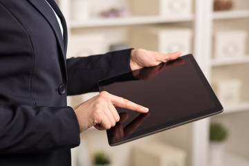 Business woman below chest using tablet in a homey environment
