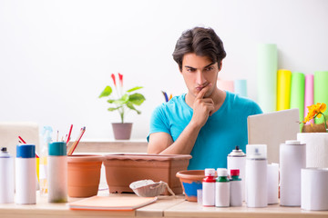 Young man decorating pottery in class