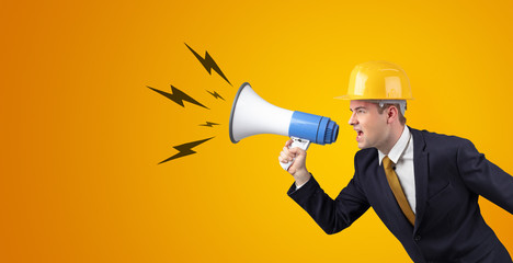 Fototapeta premium Young architect constructor yelling with megaphone and copyspace