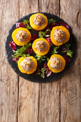Delicious appetizer peaches stuffed with tuna and decorated with walnuts close-up. Vertical top view