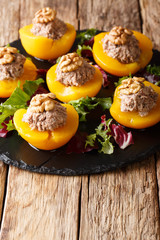 Sweet juicy peaches stuffed with tuna mousse and decorated with walnuts closeup. vertical