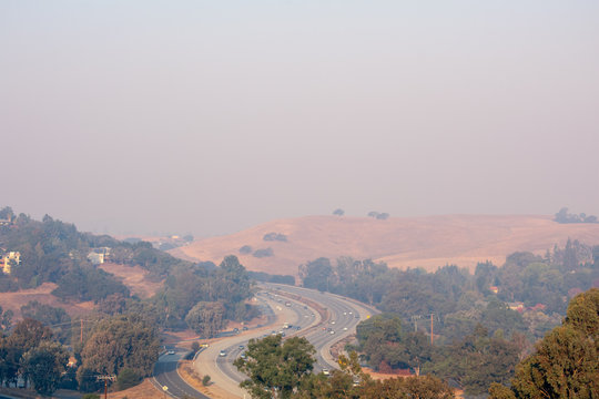 Aeril bird's eye view of light morning traffic on California highway 280 with grey haze from wild forest fire