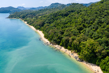 Obraz premium Aerial drone view of an empty tropical sandy beacj surrounded by lush green forest