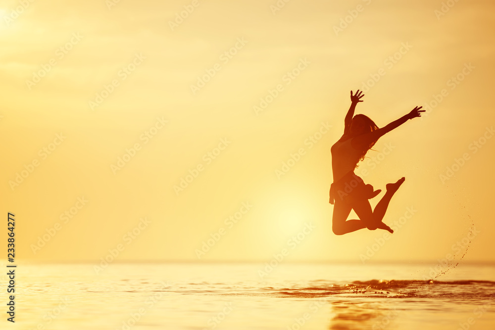 Wall mural happy woman jumps lake water sunset