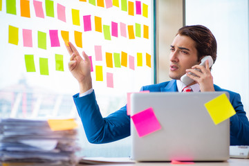 Young handsome employee with many conflicting priorities   