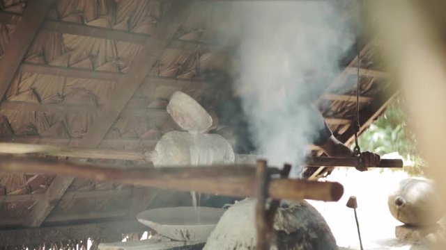 Beautiful scene, in the cabin in the Amazon rainforest, where the rubber tapper makes the artisanal process to transform the latex into rubber, amid a lot of smoke.